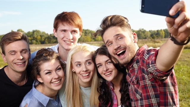 スマホで撮影する笑顔の男女たち